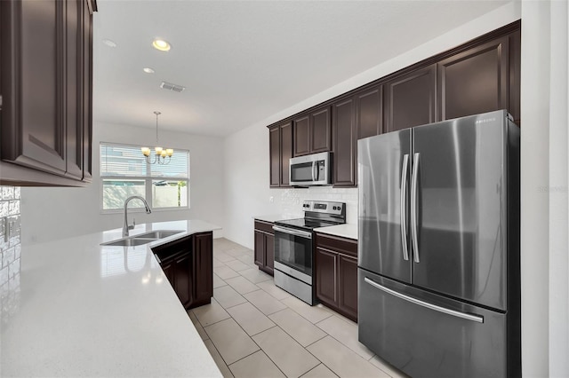 kitchen with stainless steel appliances, sink, decorative backsplash, hanging light fixtures, and a chandelier