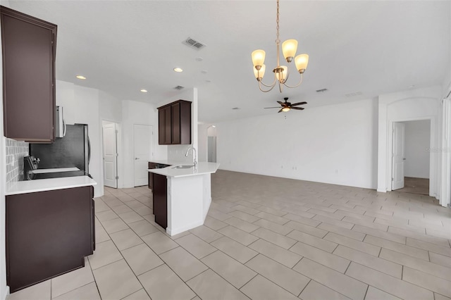 kitchen featuring range, hanging light fixtures, tasteful backsplash, dark brown cabinets, and ceiling fan with notable chandelier