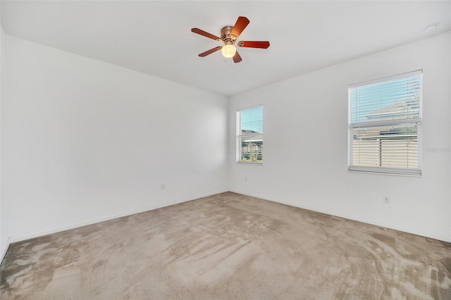 spare room with ceiling fan and light colored carpet