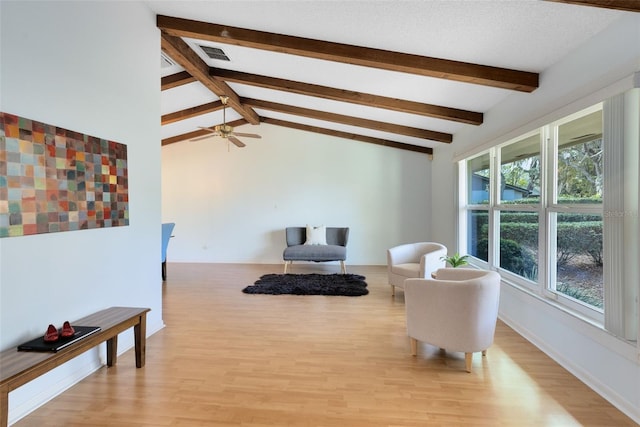 sitting room featuring ceiling fan, lofted ceiling with beams, and light hardwood / wood-style flooring