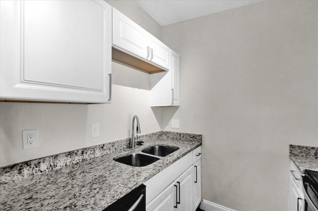 kitchen with white cabinets, light stone counters, and sink