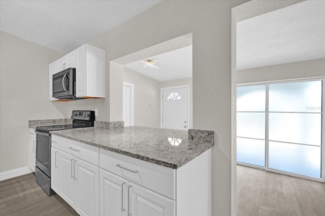 kitchen featuring white cabinetry, kitchen peninsula, appliances with stainless steel finishes, wood-type flooring, and light stone countertops