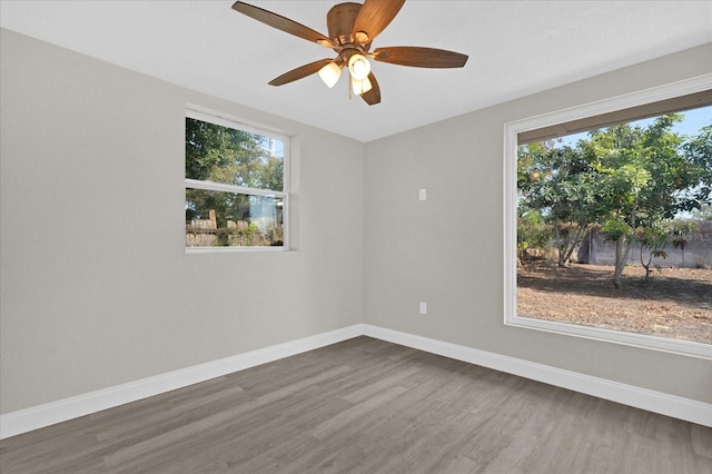 empty room featuring ceiling fan, dark hardwood / wood-style flooring, and a healthy amount of sunlight