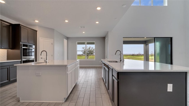 kitchen with dark brown cabinets, a large island, and sink