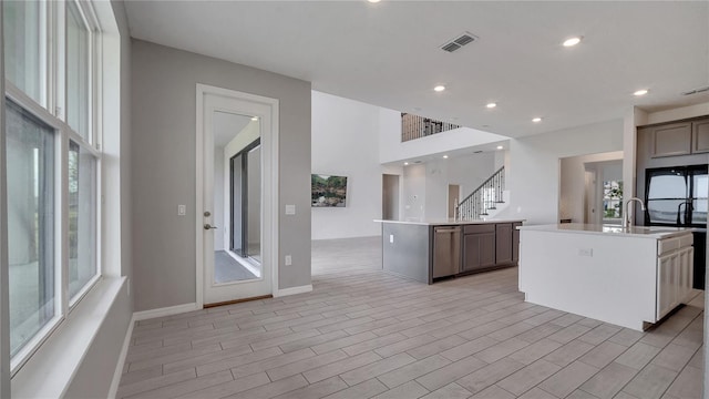 kitchen with fridge, a wealth of natural light, and a kitchen island with sink