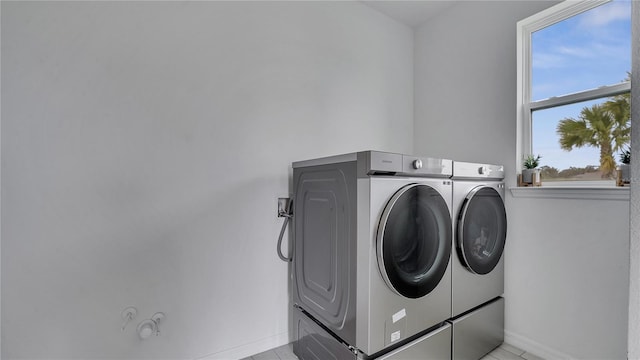 clothes washing area featuring light tile patterned floors and washer and dryer