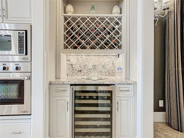 interior space with light stone counters, backsplash, wine cooler, and appliances with stainless steel finishes