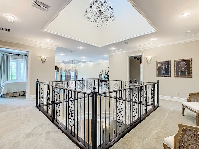 hall with a chandelier, ornamental molding, a tray ceiling, and carpet flooring