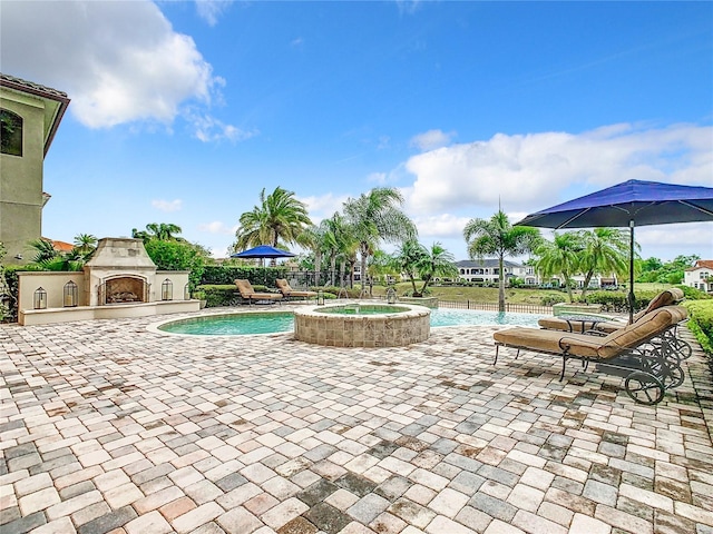 view of pool featuring a tiled fireplace, a patio, and an in ground hot tub