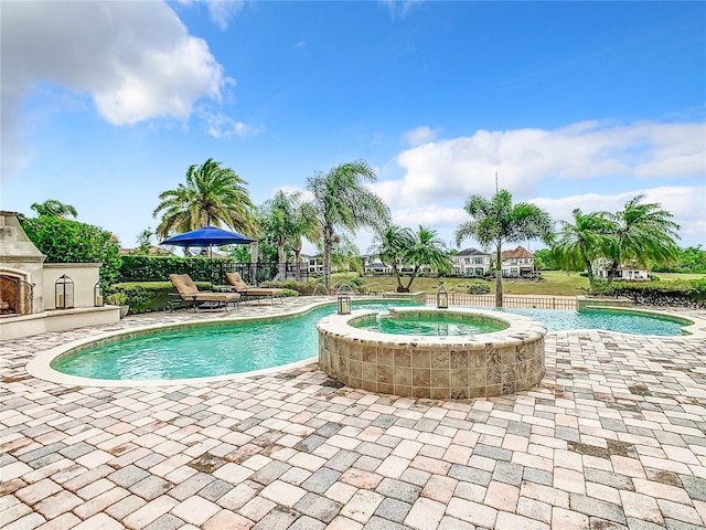 view of pool featuring a patio, an outdoor fireplace, pool water feature, and an in ground hot tub