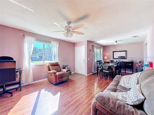 living room featuring hardwood / wood-style floors, a textured ceiling, and ceiling fan