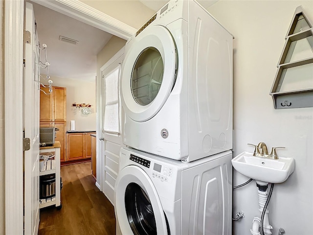 laundry room featuring sink, stacked washer / dryer, and dark hardwood / wood-style floors