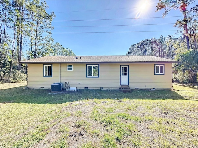 rear view of property with central AC unit and a yard