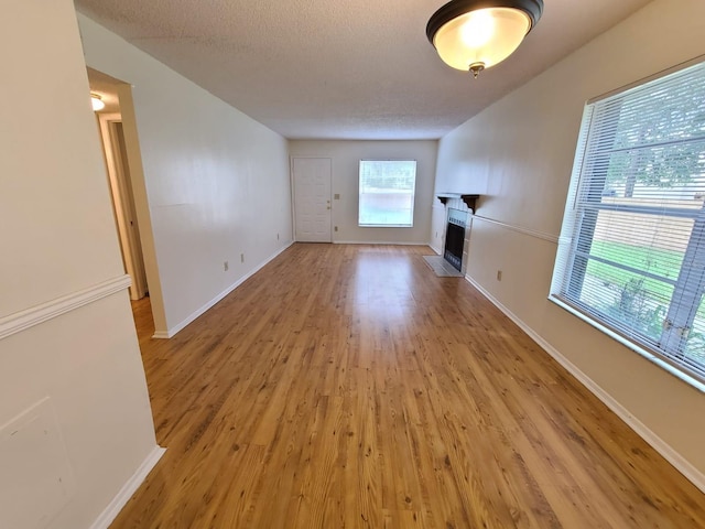 unfurnished living room with a textured ceiling, light wood-type flooring, and plenty of natural light