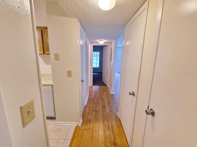 hall with a textured ceiling and light wood-type flooring