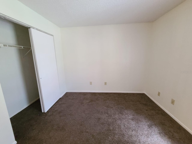 unfurnished bedroom featuring a closet and dark carpet