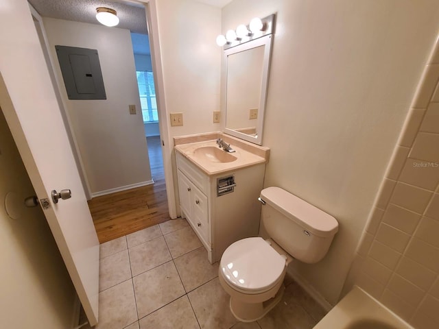 bathroom featuring tile patterned flooring, toilet, vanity, electric panel, and a textured ceiling