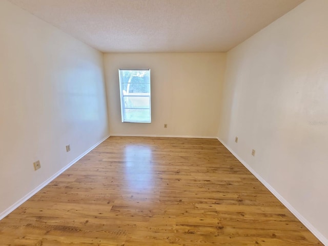 spare room featuring a textured ceiling and light hardwood / wood-style flooring