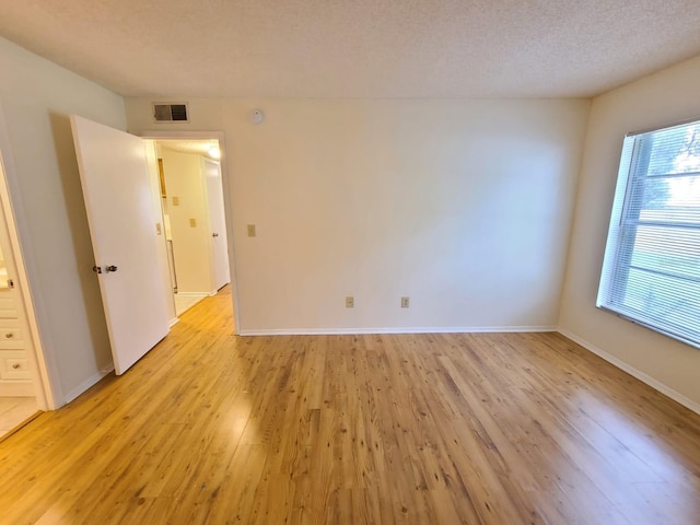 spare room featuring light hardwood / wood-style floors and a textured ceiling