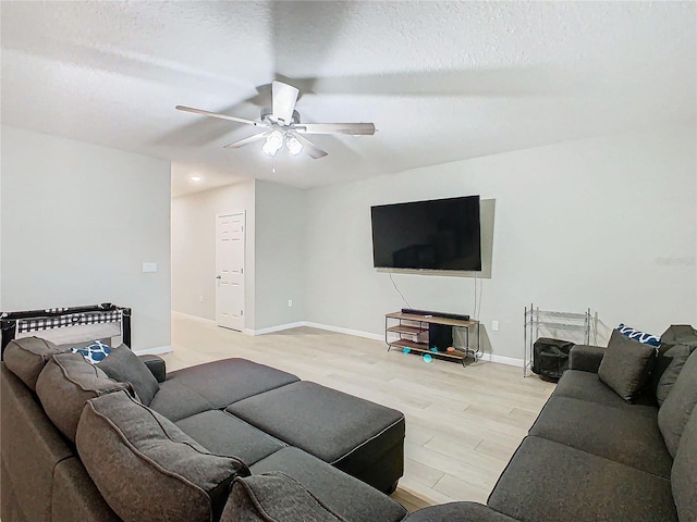 living room with ceiling fan, light hardwood / wood-style floors, and a textured ceiling