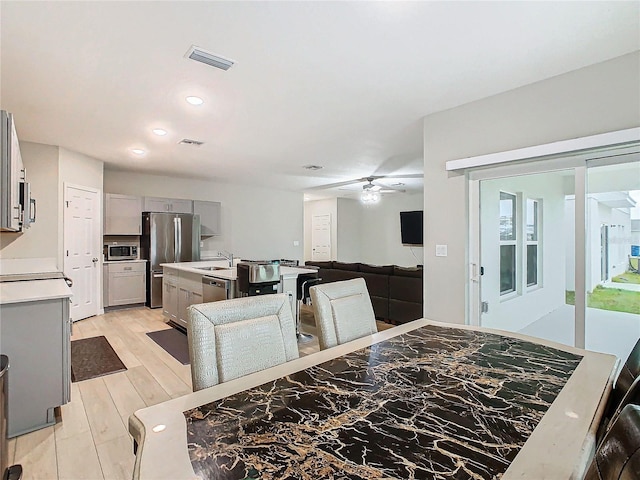 dining space with sink, ceiling fan, and light wood-type flooring