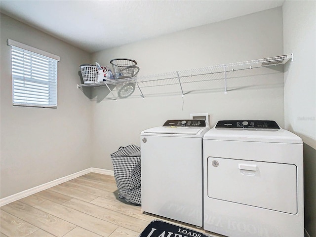 clothes washing area with light wood-type flooring and washer and clothes dryer