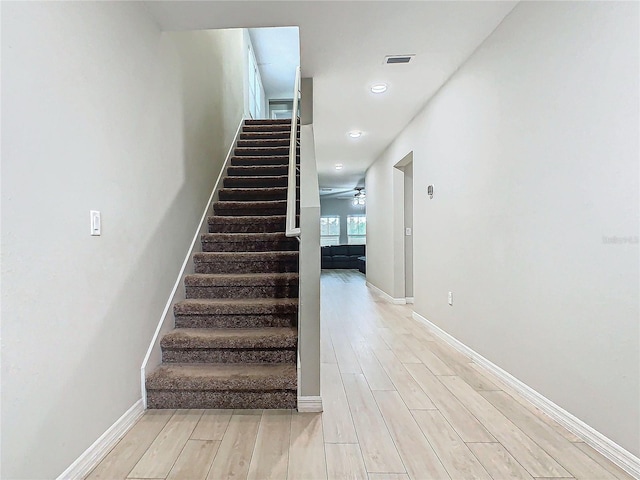 stairs with wood-type flooring and ceiling fan