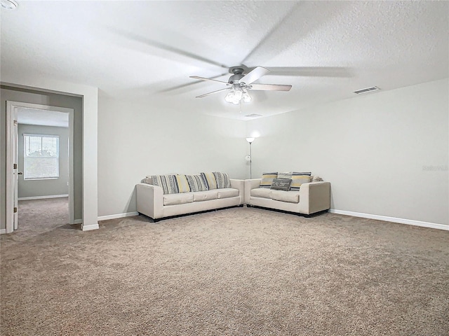 carpeted living room featuring ceiling fan and a textured ceiling