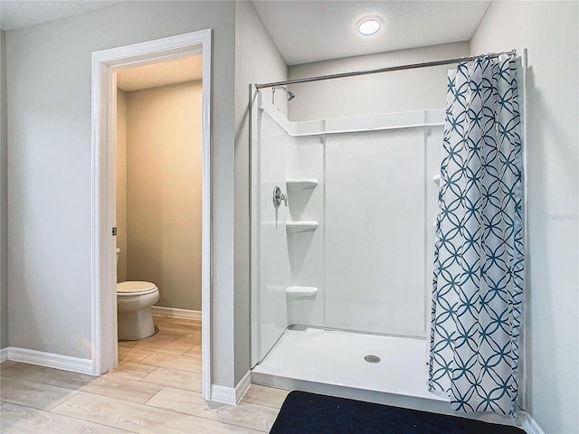 bathroom with toilet, a shower with shower curtain, and hardwood / wood-style floors