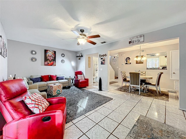 tiled living room featuring a textured ceiling and ceiling fan with notable chandelier