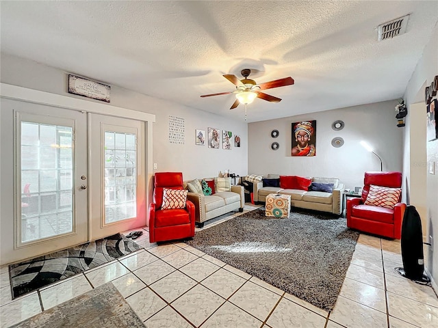 tiled living room featuring ceiling fan, a textured ceiling, and french doors