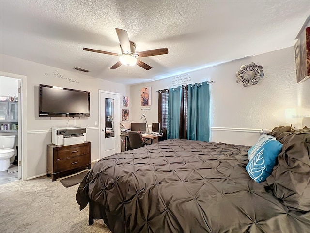 carpeted bedroom featuring ceiling fan, ensuite bath, and a textured ceiling