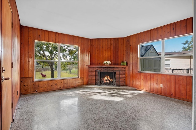 unfurnished living room featuring a fireplace and wood walls