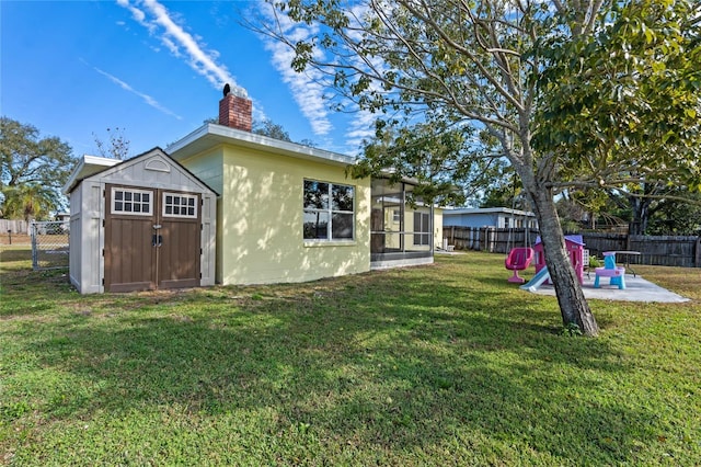 exterior space with a playground, a patio, a sunroom, and a storage shed