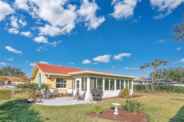 rear view of house featuring a lawn and a patio