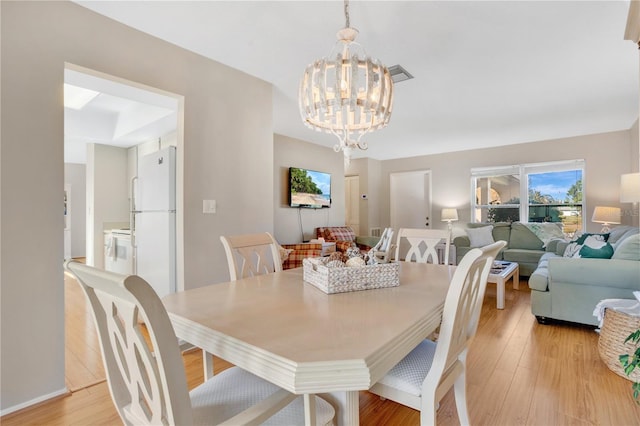 dining room with light hardwood / wood-style flooring and a chandelier