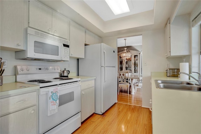 kitchen with decorative light fixtures, a notable chandelier, sink, white appliances, and light hardwood / wood-style flooring