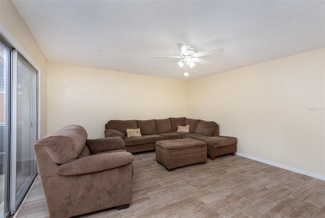 living room featuring a textured ceiling, ceiling fan, and light hardwood / wood-style floors