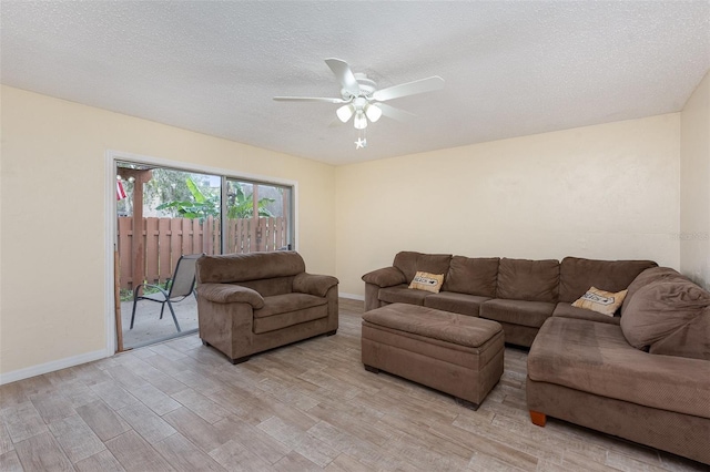 living room featuring ceiling fan, a textured ceiling, and light hardwood / wood-style flooring