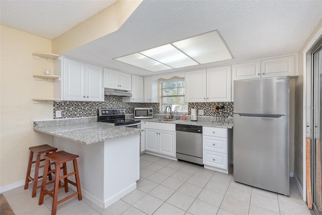 kitchen with kitchen peninsula, sink, white cabinetry, appliances with stainless steel finishes, and light tile patterned floors