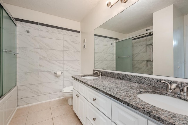 full bathroom with shower / bath combination with glass door, tile patterned floors, vanity, tile walls, and toilet