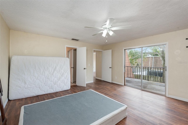 unfurnished bedroom with ceiling fan, access to outside, dark hardwood / wood-style flooring, and a textured ceiling