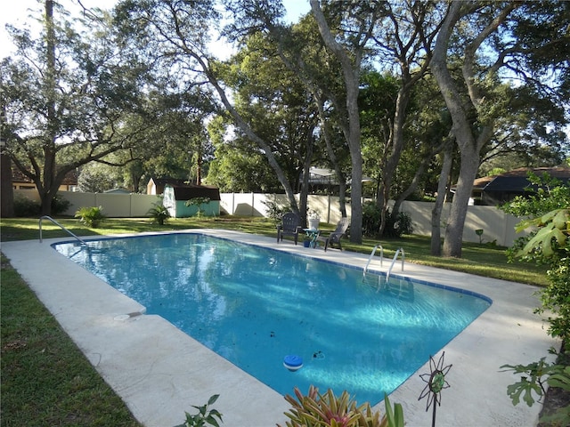 view of swimming pool featuring a storage unit and a yard