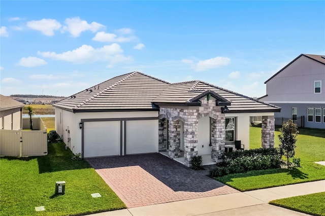 view of front of house featuring a garage, a front lawn, and a water view