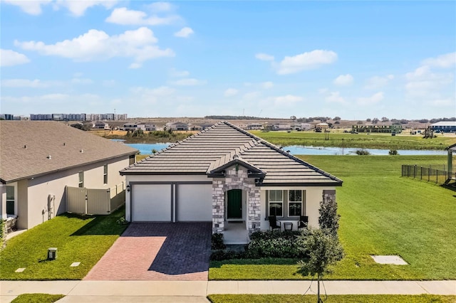 ranch-style home with a garage, a front lawn, and a water view