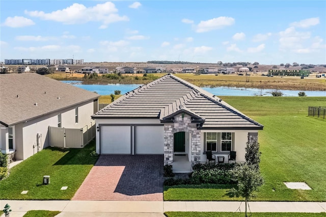 ranch-style home with a garage, a front lawn, and a water view