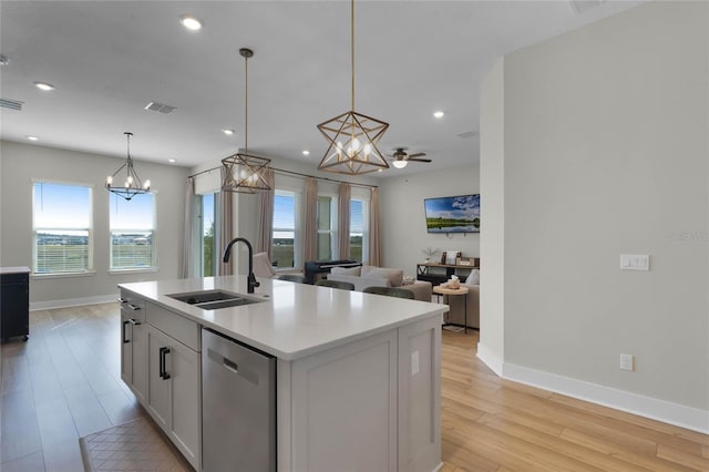 kitchen with sink, a center island with sink, light wood-type flooring, stainless steel dishwasher, and pendant lighting