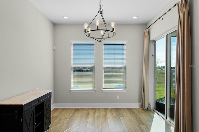 unfurnished dining area featuring a notable chandelier and light hardwood / wood-style flooring