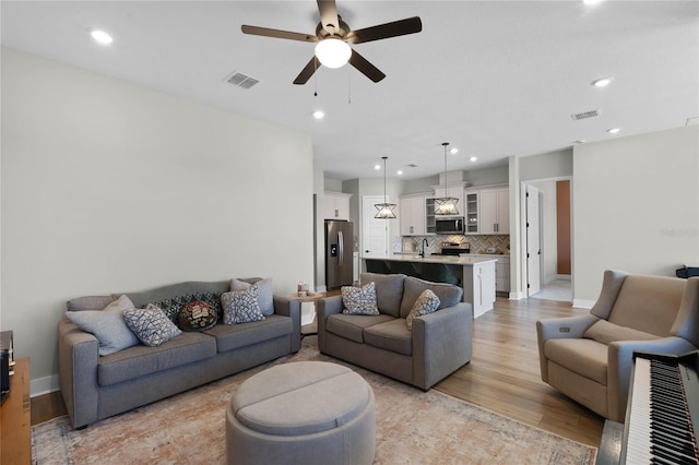 living room featuring light hardwood / wood-style flooring and ceiling fan