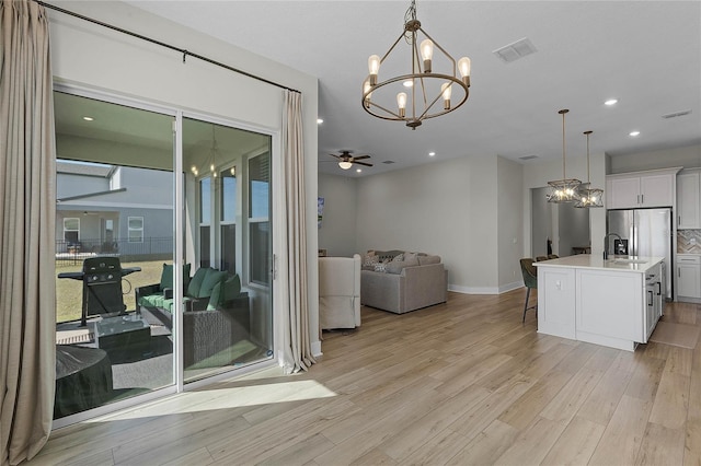 dining space featuring sink, ceiling fan with notable chandelier, and light hardwood / wood-style flooring